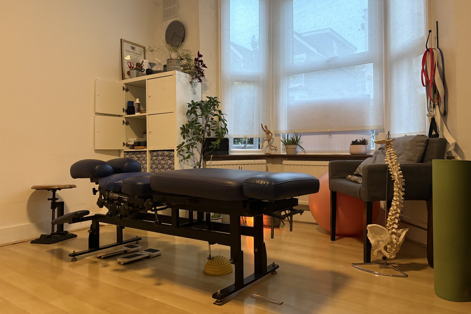 Chiropractic treatment table beside a spine model in a bright treatment room