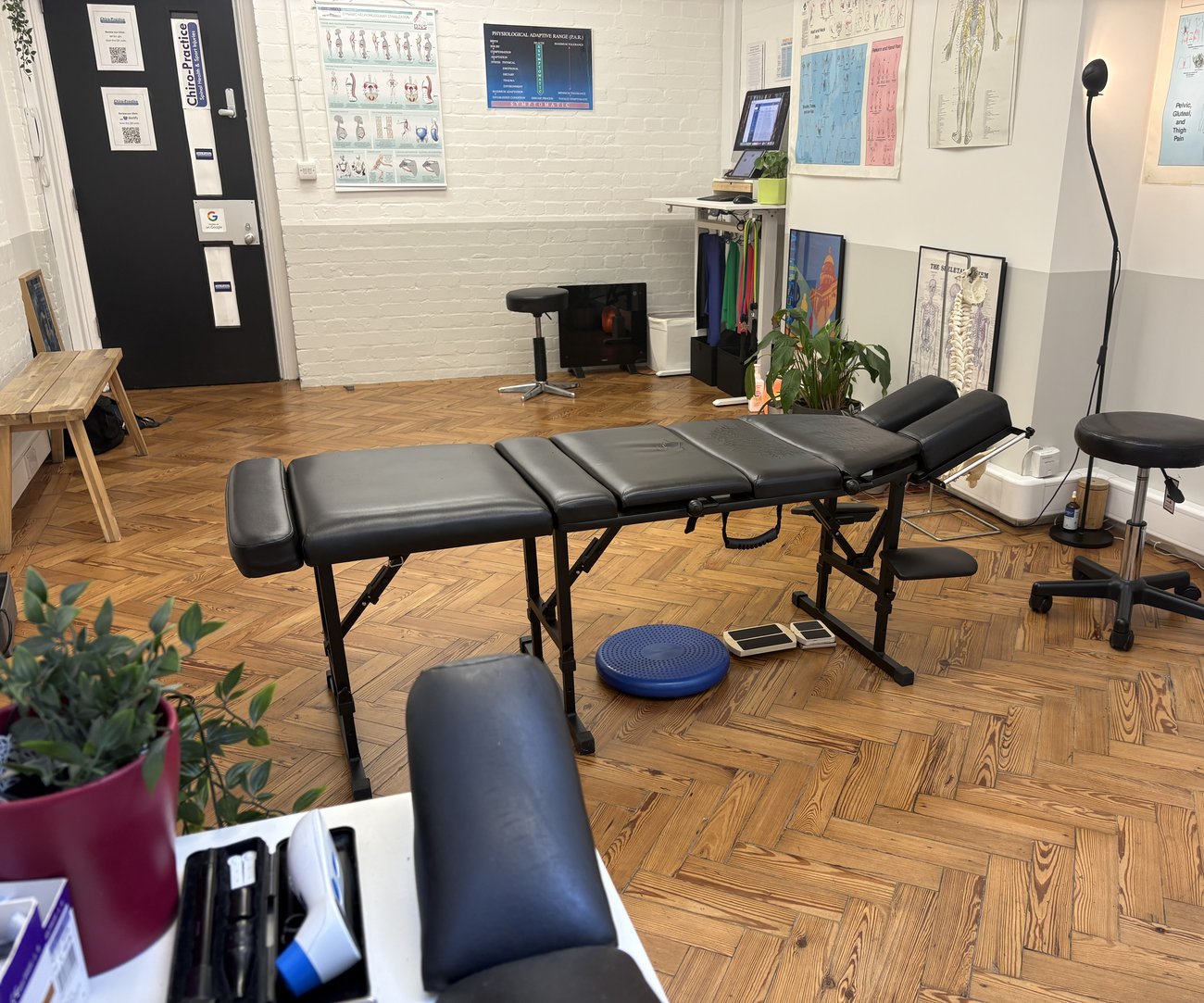 Treatment room at the City of London clinic with a chiropractic table and parquet floor
